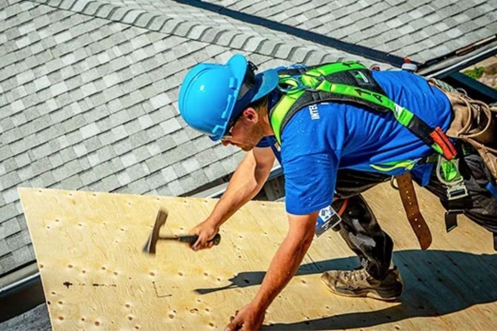 A worker in a blue shirt and safety vest conducts roof maintenance in Washington, DC, highlighting our professional services.